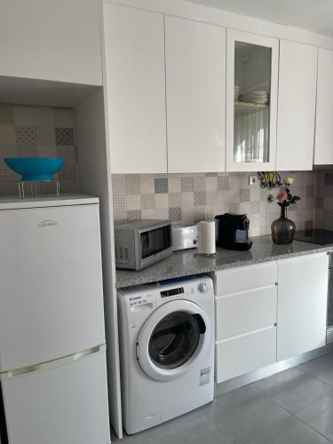 a kitchen with a washing machine and a microwave at Casa Miradouro in Nazaré