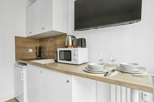 une cuisine avec un comptoir, un four micro-ondes et des verres dans l'établissement 531 Suite Bugeaud - Superbe Appartement à Paris, à Paris
