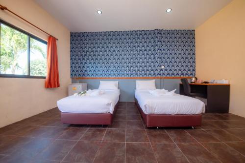 Habitación con 2 camas, escritorio y ventana. en NaLinNaa Resort Buriram ณลิ์ณน่า รีสอร์ท บุรีรัมย์, en Buriram