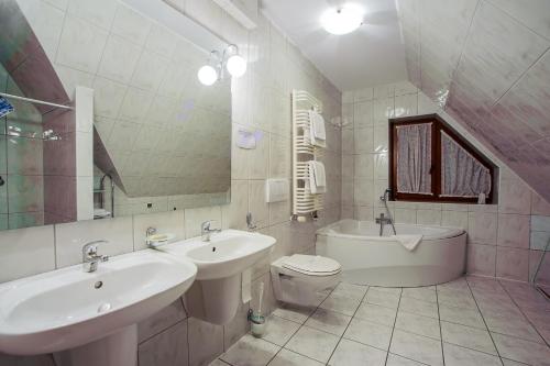 y baño con 2 lavabos, bañera y aseo. en Apartamenty Jan, en Szczawnica