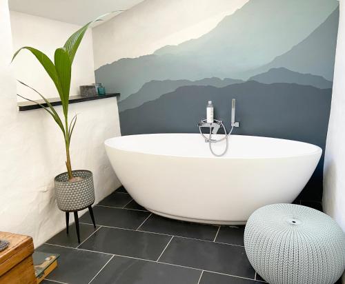 La salle de bains est pourvue d'une baignoire et d'une fresque murale de montagne. dans l'établissement Close to Snowdon with Mountain views of Snowdonia, à Caernarfon