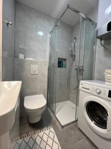 a bathroom with a shower toilet and a washing machine at Apartman Andrijanic in Grude