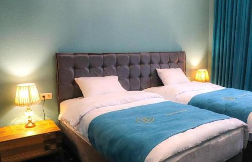 two beds in a room with two lamps on tables at Belona Hotel in Kutaisi