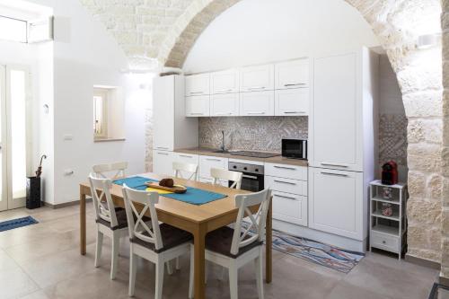 cocina con mesa de madera y armarios blancos en Da zia Giovanna Apartment, en Manfredonia