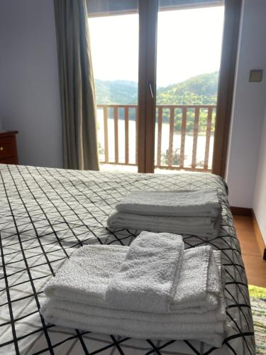 a bed with towels on it with a balcony at Casa do Paradela in São Pedro