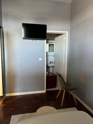 a room with a chair and a television on the wall at Residencial Funchal in Funchal