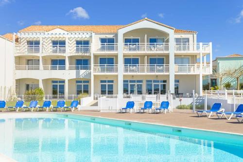 un complexe avec une piscine et des chaises bleues dans l'établissement L'Estran - Appt Confortable avec Piscine Chauffée, à Saint-Jean-dʼOrbetiers