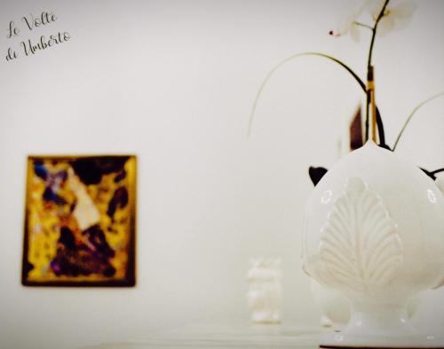a white vase sitting on a table next to a painting at Le volte di Umberto in Sogliano Cavour