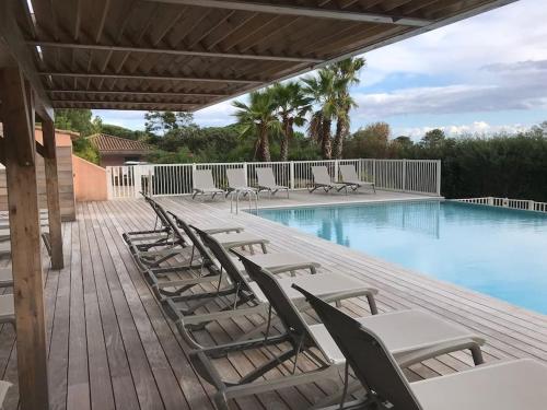 une rangée de chaises assises sur une terrasse à côté d'une piscine dans l'établissement Résidence Les Hameaux de Sta Giulia - N1 - Vue mer - Piscine chauffée - Plage 200 m, à Porto-Vecchio