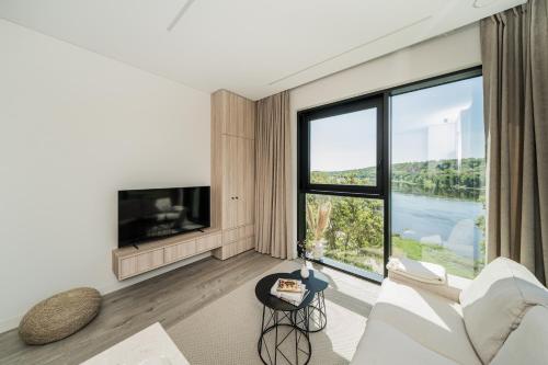 een woonkamer met een witte bank en een groot raam bij Kaunorama Riverside Suite in Kaunas