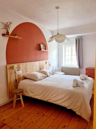 une chambre avec un grand lit avec une tête de lit rouge dans l'établissement Grand duplex au coeur du centre historique, à Paray-le-Monial