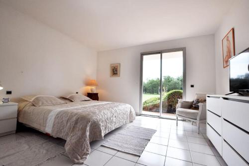 une chambre blanche avec un lit et une télévision dans l'établissement Villa Haut Standing avec Piscine, Vue sur Golf, à Saint-Cyprien