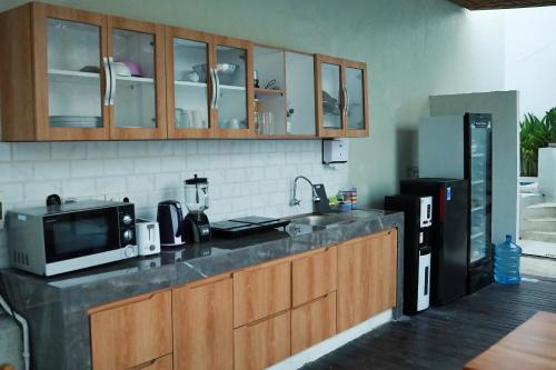 a kitchen with a counter top with a microwave and a refrigerator at KAYA Uluwatu in Uluwatu