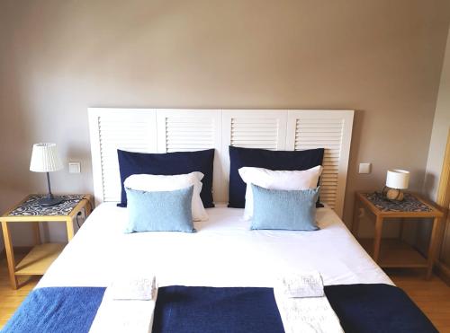 a bedroom with a large white bed with blue pillows at Palácio Garden's House by LovelyStay in Porto