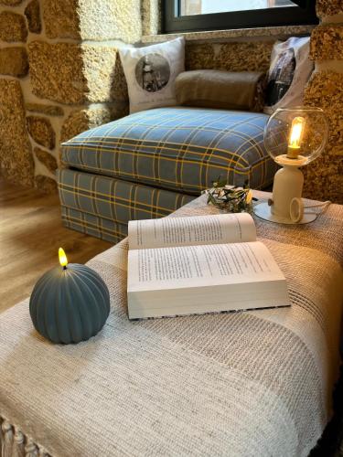 a table with a book and a candle on a bed at Senhora da Estrela AL in Seia
