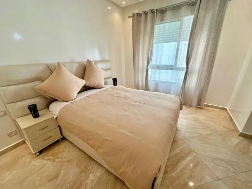 een slaapkamer met een groot bed en een raam bij superbe appartement en résidence balnéaire in Bouznika