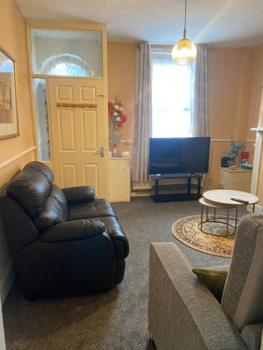 a living room with a leather couch and a television at White and Sandstone Astley Bridg in Bolton