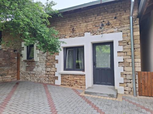 een stenen huis met een zwarte deur en een raam bij Под шарената сянка in Kŭrpachevo