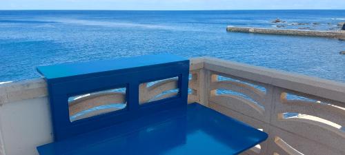 un banco azul sentado en una pared con vistas al océano en Vv Puesta de Sol en Alojera