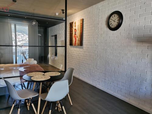 uma sala de jantar com uma parede de tijolos brancos e um relógio em Modern Apartments em Cidade do Cabo