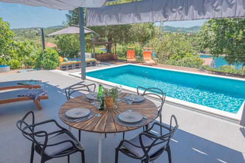 a table and chairs next to a swimming pool at Kuća Mali Raj - Little Paradise in Šibenik