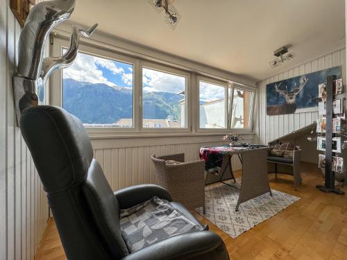 salon z krzesłem, stołem i oknami w obiekcie Stadt & See Appartement Penthouse inkl MIC Card w mieście Spittal an der Drau