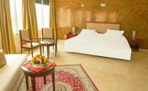 Un dormitorio con una cama y una mesa con un bol de fruta en Hotel Angle Atlas, en El Ksiba