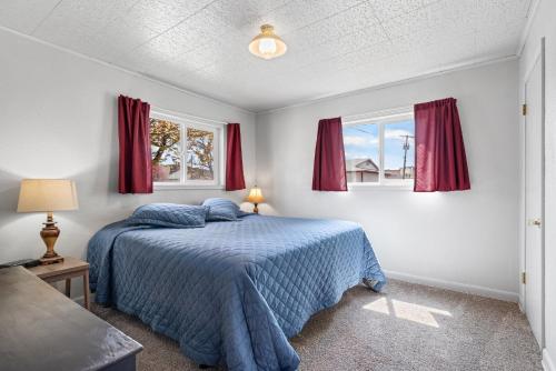 una camera con un letto blu e due finestre di The Chick Inn a Baker City
