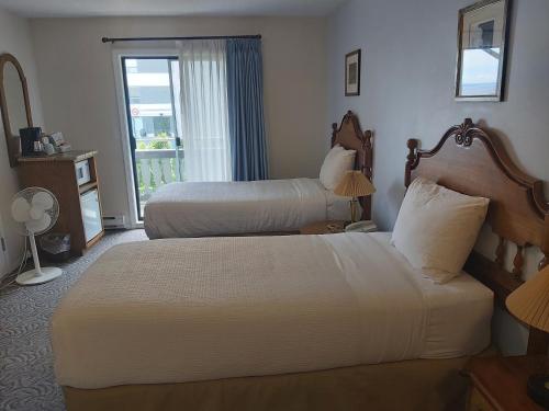 um quarto de hotel com duas camas e uma janela em Heron's Landing Hotel em Campbell River