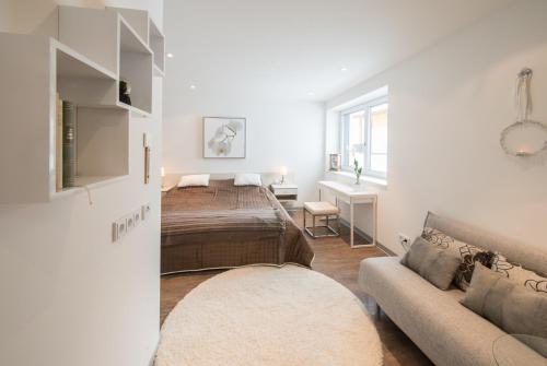 a white bedroom with a bed and a couch at Apartmenthaus Mountainvista in Kleinarl