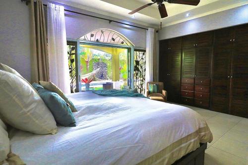 a bedroom with a large bed with a large window at Villa Encantada By Vacation Pura Vida in Esterillos