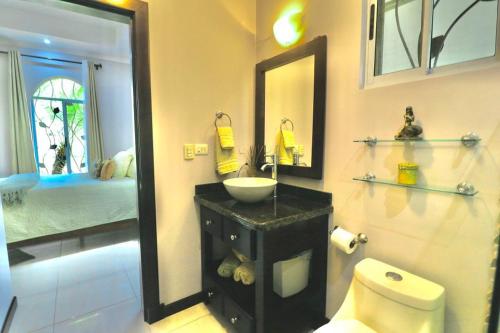 a bathroom with a sink and a toilet and a mirror at Villa Encantada By Vacation Pura Vida in Esterillos
