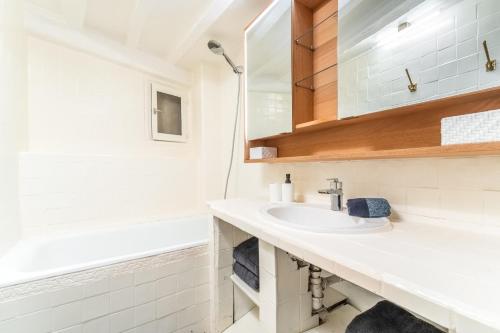 La salle de bains blanche est pourvue d'un lavabo et d'une baignoire. dans l'établissement Charming Flat Montorgueil, à Paris
