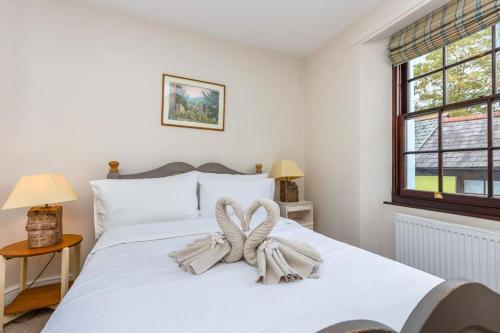a bedroom with a white bed with a bow on it at River Garden Cottage in Dean