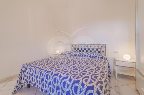 Una cama azul y blanca en un dormitorio blanco en Appartamento Le Conchiglie - Goelba, en Portoferraio