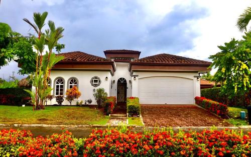 a house with a garage and flowers in front of it at Villa Paraiso By Vacation Pura Vida in Bejuco