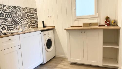 une cuisine blanche avec un lave-linge et un sèche-linge. dans l'établissement Chaleureuse Échappée : Commodités, Calme, Confort, à Angers