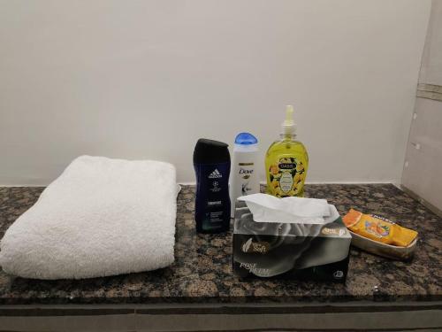 a counter with a towel a bottle of soap and other items at One Bed Apartment In GoldCrest Mall And Residency in Lahore
