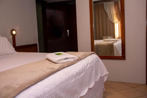 a bed with a mirror and a towel on it at HOTEL DOMHOF in Blumenau