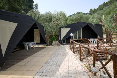 un paio di tende nere con tavoli e sedie di Village Valle D'Oro ApartHotel a San Menaio