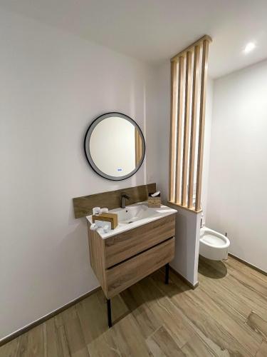 une salle de bain avec un lavabo et un miroir et des toilettes dans l'établissement appartements guesthouse1 et guesthouse2 sword beach, à Colleville-Montgomery