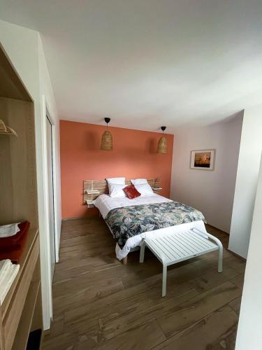 une chambre avec un lit avec un mur orange dans l'établissement appartements guesthouse1 et guesthouse2 sword beach, à Colleville-Montgomery