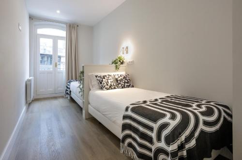 ein Schlafzimmer mit einem Bett mit einer schwarzen und weißen Decke in der Unterkunft Apartamento Pagasarri, Bilbaohost in Bilbao