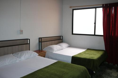 2 camas en una habitación con ventana en Aparta Suite Torre De Prado Penthouse, en Medellín