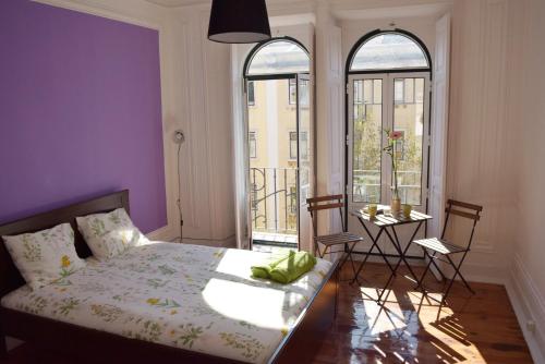 a bedroom with purple walls and a bed and a table at Nations Rooms in Lisbon