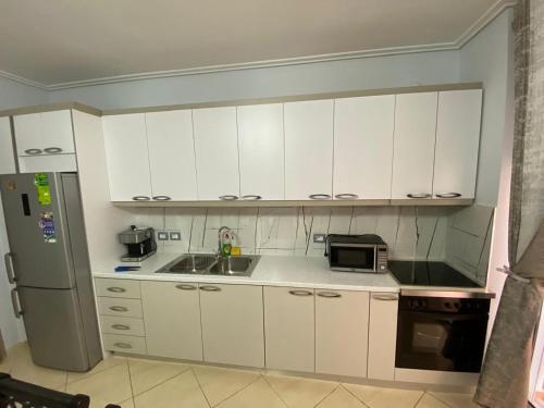a kitchen with white cabinets and a sink and a refrigerator at Olive Tree Apartment in Sarandë