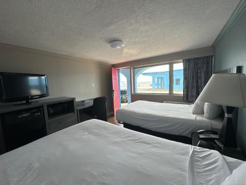 a hotel room with two beds and a flat screen tv at Econo Lodge Galveston Seawall in Galveston