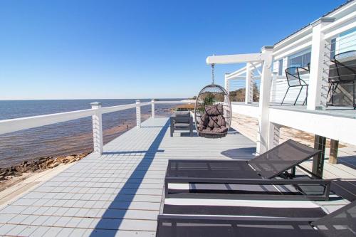 a porch with chairs and a swing on the beach at Private Waterfront Beach House with Fire-pit in Ocean Springs
