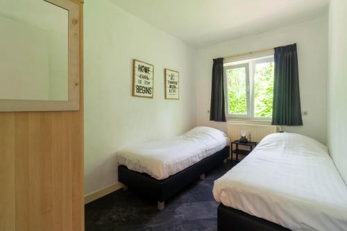 2 camas en una habitación pequeña con ventana en Holiday Home Eekhoornbosch en Otterlo