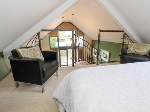 a bedroom with two chairs and a bed and a staircase at The Nail Shed in Scarborough